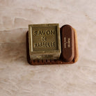 A wooden soap dish and nail brush with a cube of soap.