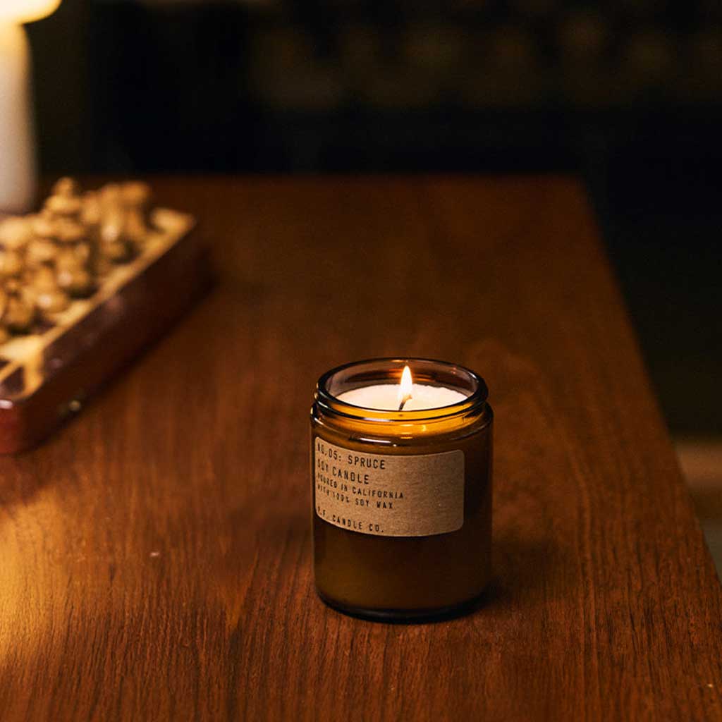 Candle in a glass jar on a wooden surface with a blurred background