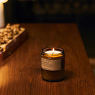 Candle in a glass jar on a wooden surface with a blurred background