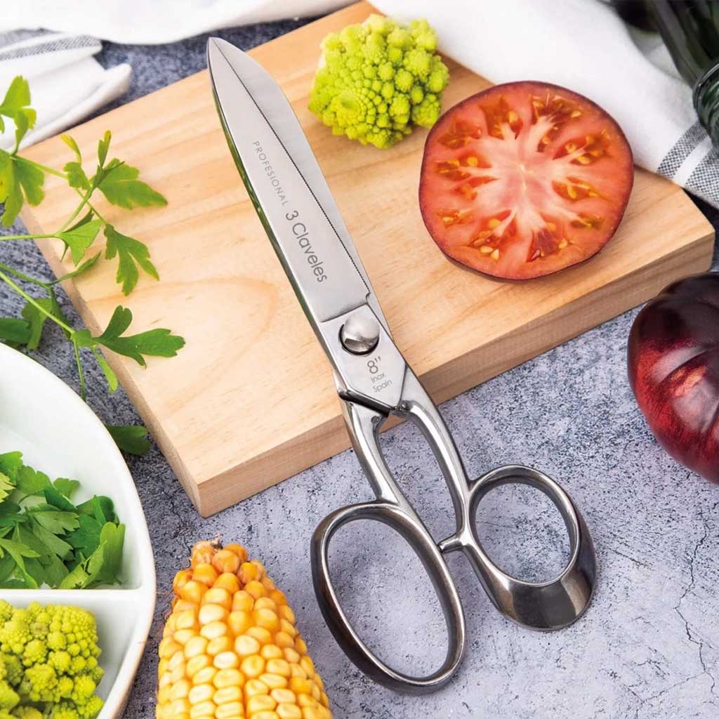 Shears on a cutting board with vegetables on a gray surface