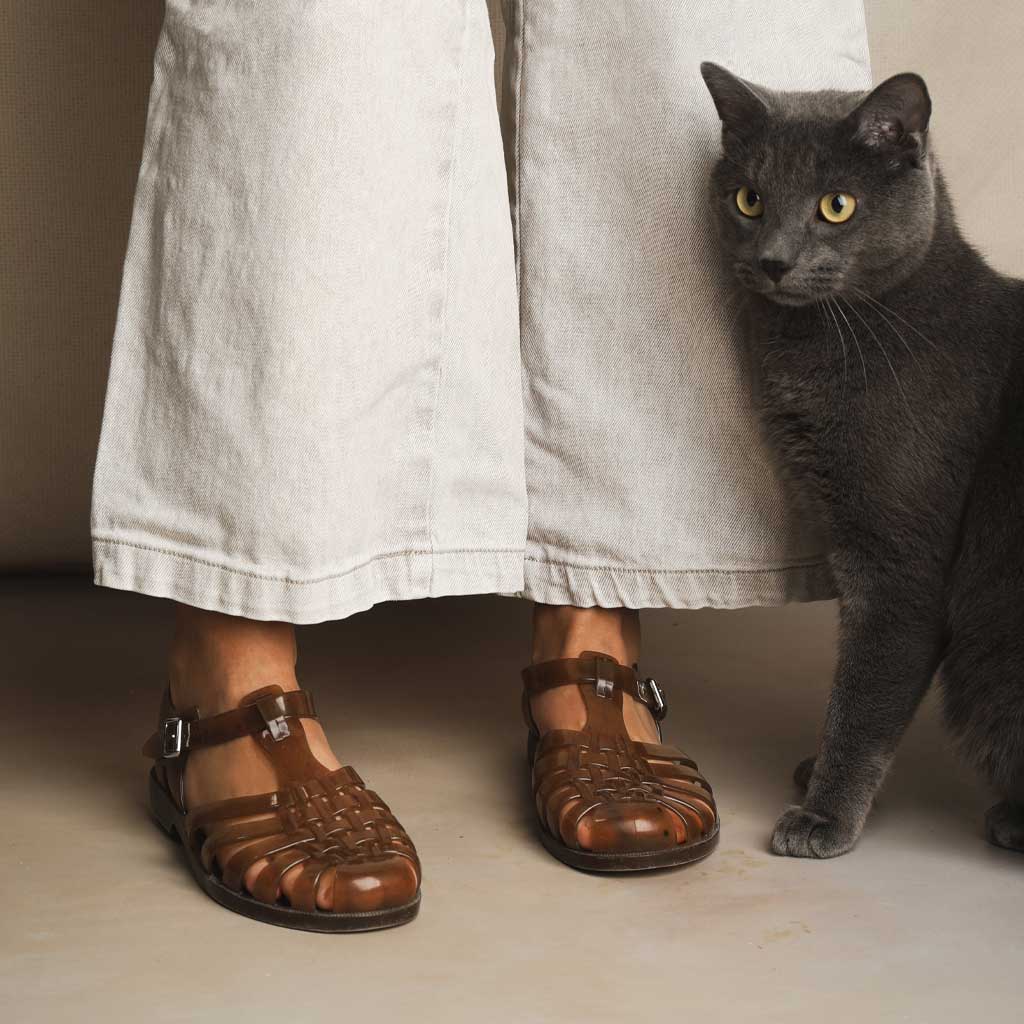 Model wearing hemp jelly sandals against light backdrop with gray cat 