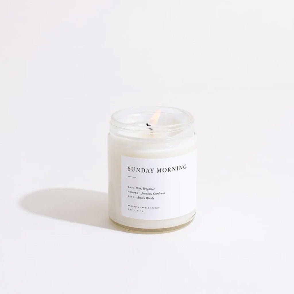 Lit candle labeled 'Sunday Morning' on a white background