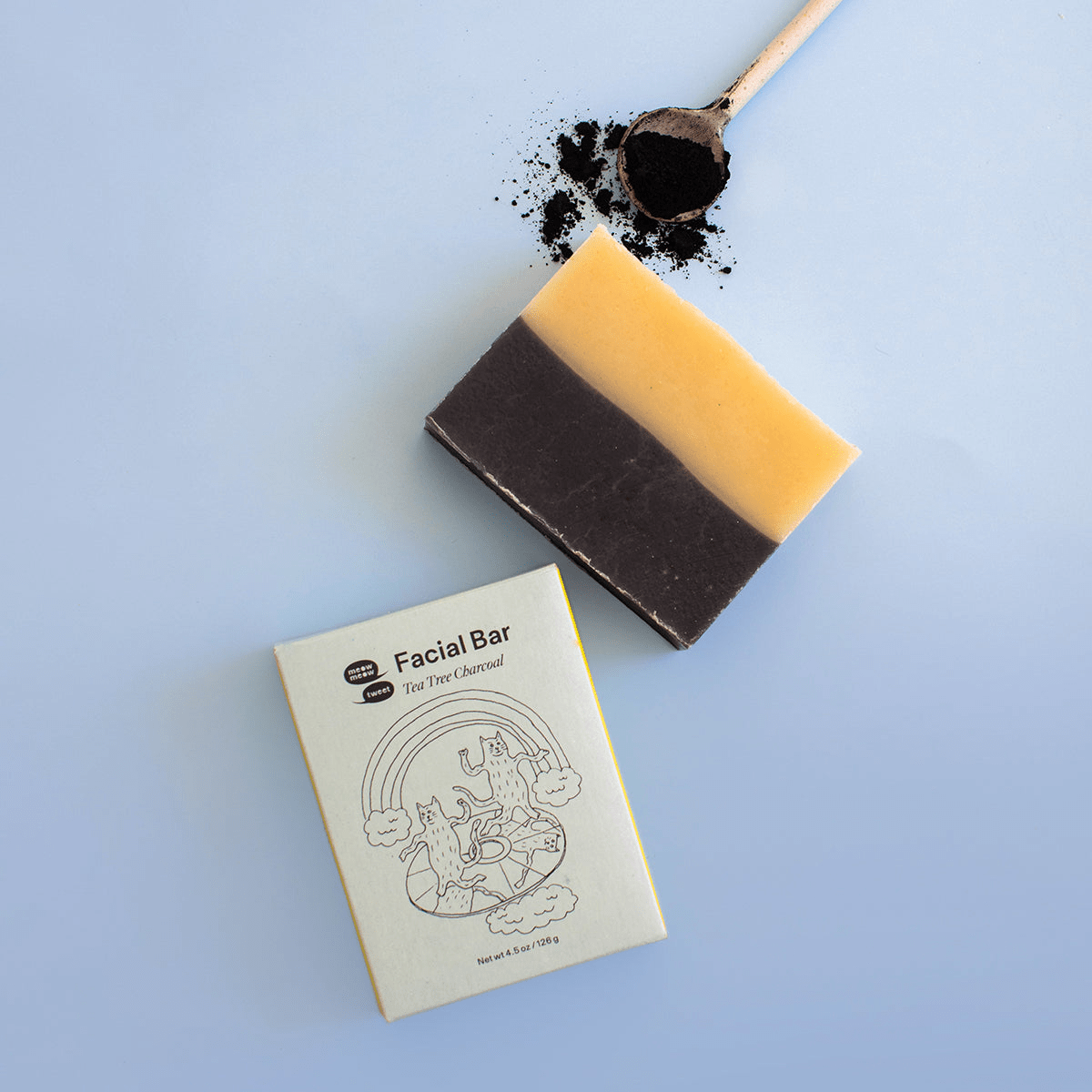 Two layered soap bar with a cardboard box labeled 'Facial Bar' on a light blue background.