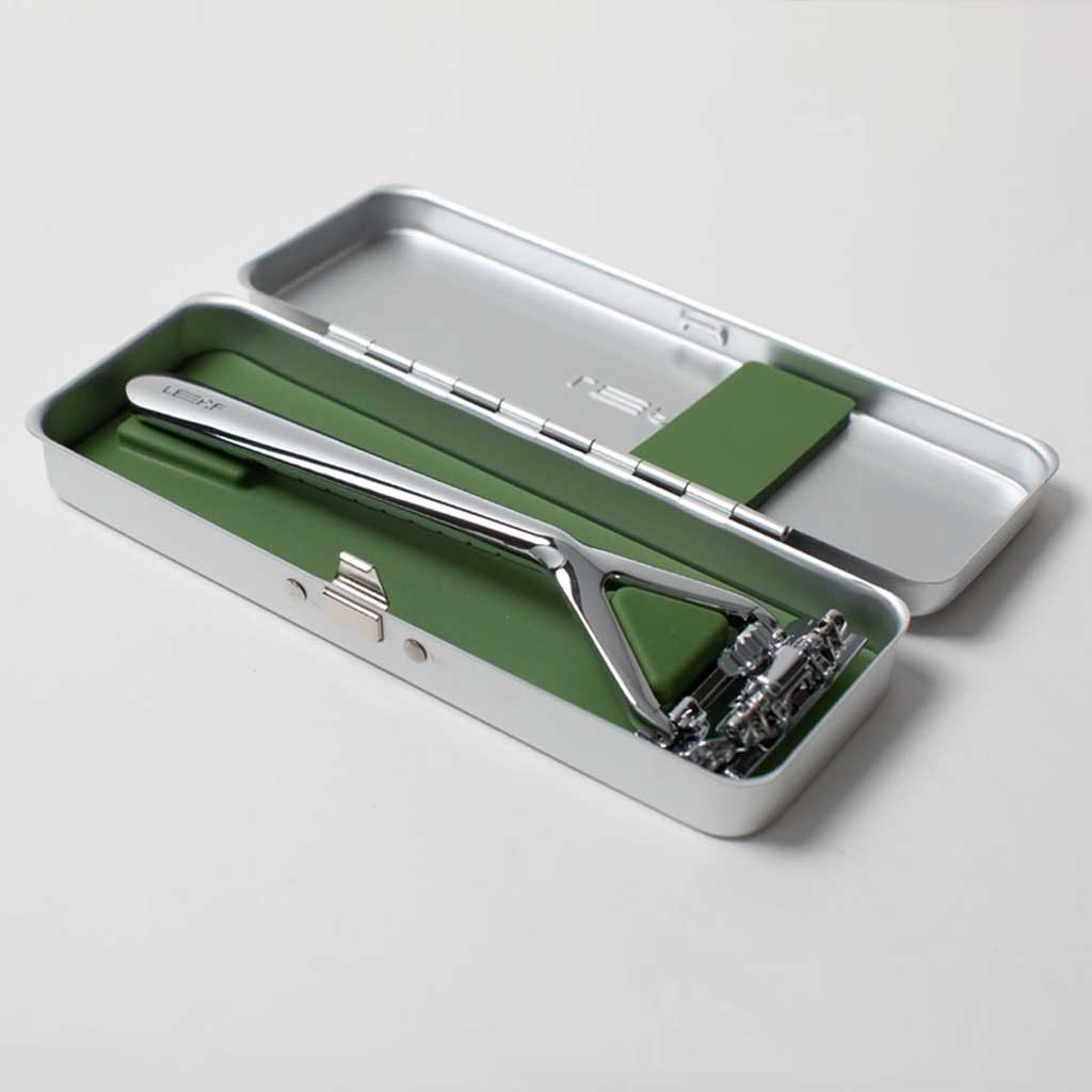 Shaving razor set in a green and silver case on a light gray background