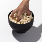 Hand reaching into popcorn popper full of popcorn