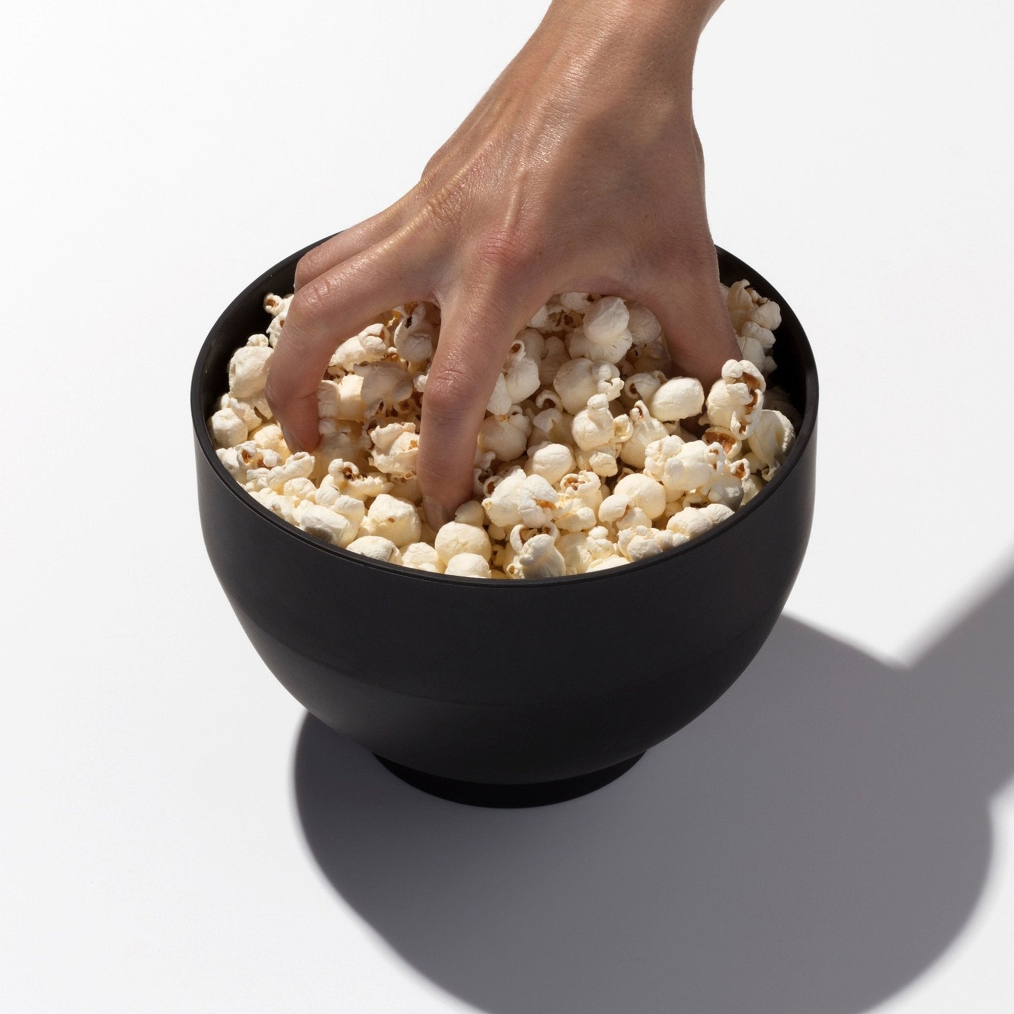 Hand reaching into popcorn popper full of popcorn