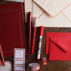 Red pens, notebook, envelopes, labels, and washi tape.