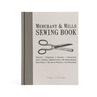 The cover of Merchant & Mills Sewing Book, showing a hardcover-bound book with an illustration of scissors on the front. 
