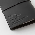 Black leather notebook cover with embossed text that reads "20th traveler's notebook" on a white background