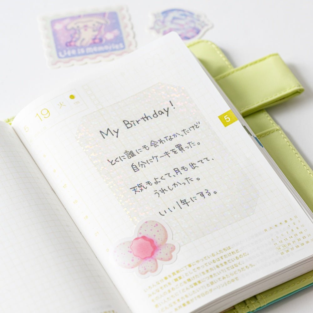 Glittery transparent sticker on Hobonichi planner page with Japanese writing showing through