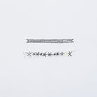 Two decorative black and white stickers with stars and gold accents laying on white surface