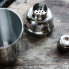 Metallic cocktail shaker components on a wooden surface