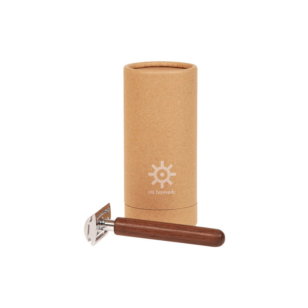 Razor with walnut wooden handle next to kraft packaging on white background