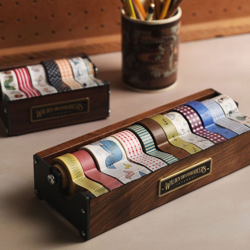 Wooden washi tape holder with colorful tapes and a cup of pencils in the background.
