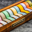 Large wooden washi tape dispenser with colorful tapes on dark background