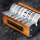 Medium wooden washi tape dispenser with patterned tapes on dark background