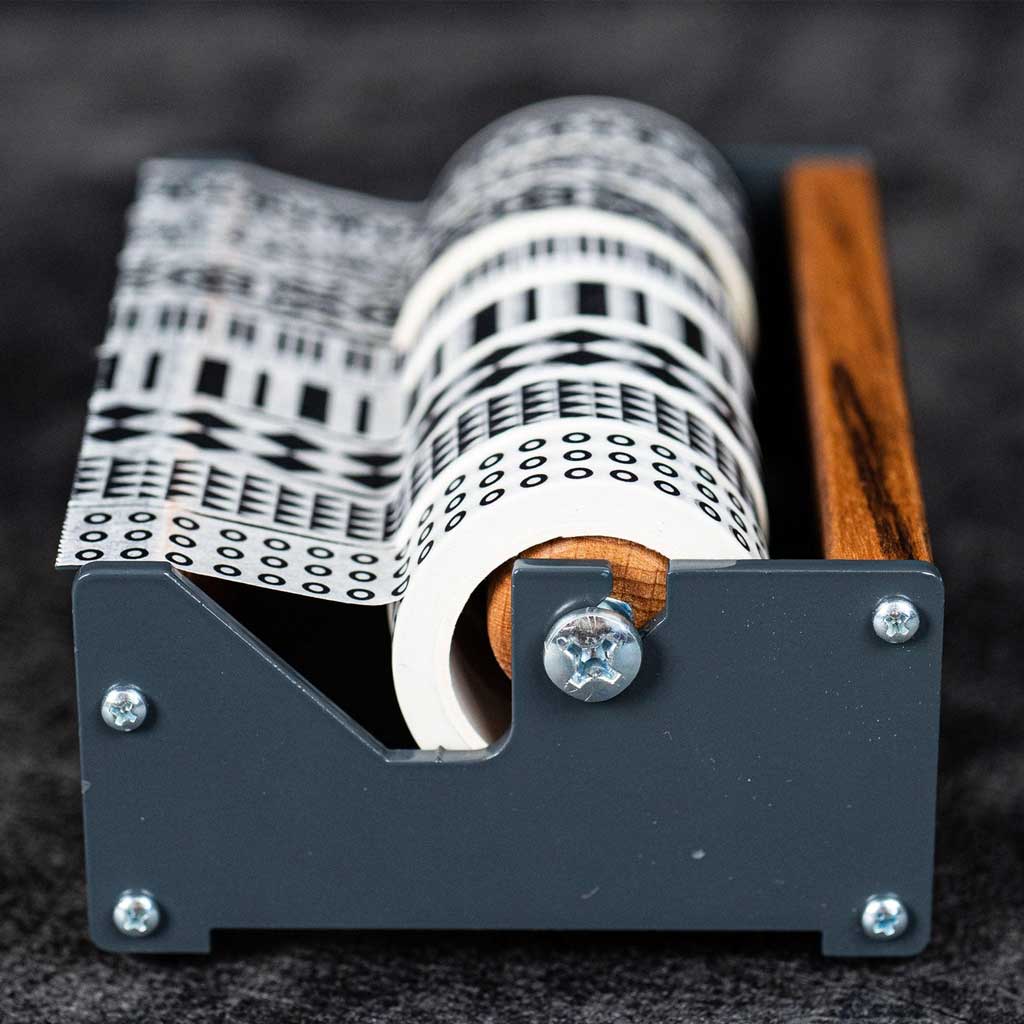 Medium wooden washi tape dispenser with patterned tapes on dark background