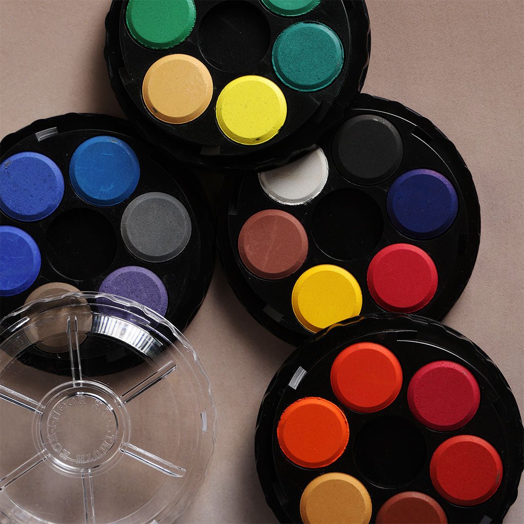 Four round, plastic trays, each with six different colors of watercolor paint, plus a clear lid. 