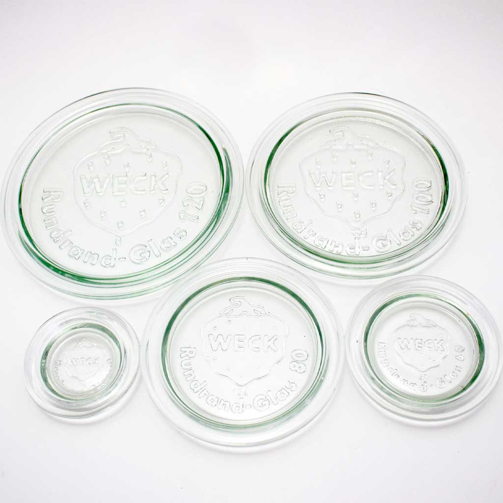 Set of five glass Weck jar lids on white background