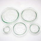 Set of five glass Weck jar lids on white background