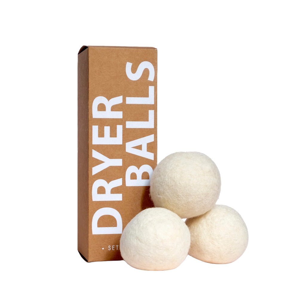 Three white wool dryer balls next to packaging on white background