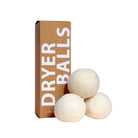 Three white wool dryer balls next to packaging on white background