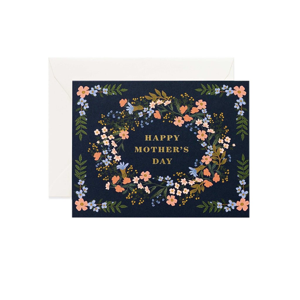A Mother's Day greeting card with a floral pattern and 'Happy Mother's Day' text in the center on a navy blue background, accompanied by a soft white envelope.