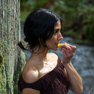 Woman applying hive lip balm against nature background
