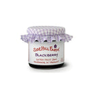 Jar of Sidehill Farm blackberry jam with a checkered lid on a white background