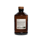 Back of brown glass bottle of orgeat syrup with wooden cap on a white background